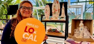 Mujer emprendedora sonriendo con un aviso en la mano que tiene el logo de Impulso Local 4.0